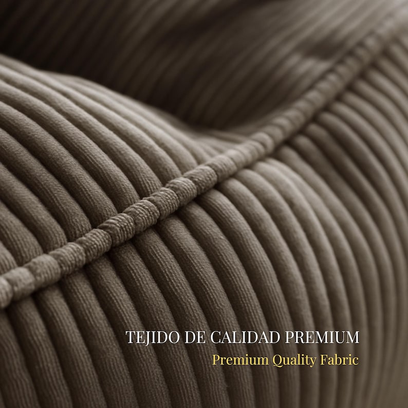 Puede incluir: Un primer plano de tela de pana color topo con crestas verticales distintivas y un detalle de costura ribeteada. El texto TEJIDO DE CALIDAD PREMIUM y Premium Quality Fabric est&aacute; impreso en letras blancas y doradas sobre la superficie.