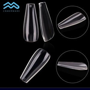May include: Clear plastic nail tips in a coffin shape. The tips are shown from different angles.