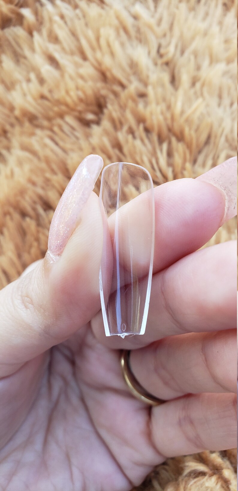 May include: Clear plastic nail tips for nail extensions. The tips are long and narrow, with a slightly curved shape.