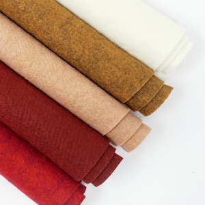 May include: Five rolls of felt fabric in various shades of red, brown, and beige. The rolls are arranged in a fan shape, with the lightest colour at the top and the darkest colour at the bottom.