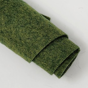 May include: A roll of dark green felt fabric. The felt is soft and has a slightly fuzzy texture.