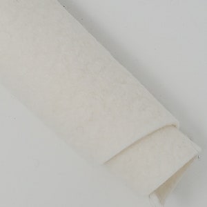 May include: A close-up of a white, rolled-up piece of felt fabric. The felt is soft and smooth, and it is perfect for crafting projects.