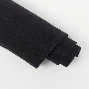 May include: A roll of black felt fabric. The felt is soft and has a slightly fuzzy texture.