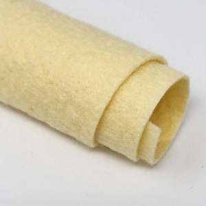 May include: A roll of off-white felt fabric. The felt is soft and has a slightly textured surface.