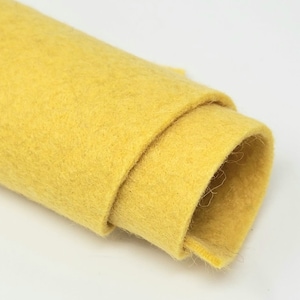 May include: A roll of yellow felt fabric. The felt is soft and has a slightly fuzzy texture.