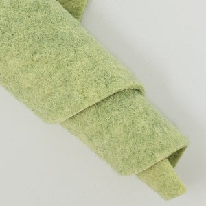 May include: A roll of light green felt fabric. The fabric is soft and has a slightly textured surface.