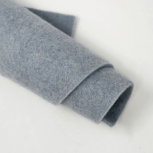 May include: A rolled-up piece of light blue felt fabric. The felt is soft and textured, with visible fibers. A small, flat piece of the same felt is visible on top. The fabric is likely used for crafts and DIY projects.