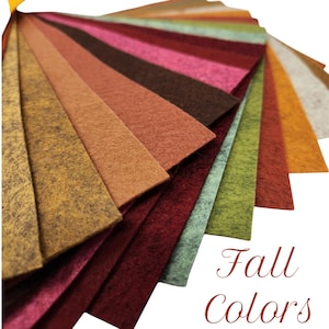 May include: A fan of felt fabric swatches in various fall colors, including shades of gold, orange, red, pink, and green. The text "Fall Colors" is displayed in a cursive font. The swatches are arranged to showcase the range of hues.