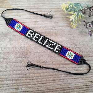 Pode incluir: Pulseira de contas pretas com a bandeira de Belize e a palavra "BELIZE" em contas brancas.