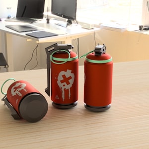 May include: Three red spray paint cans with a white cross and green accents. The cans have a black handle and a black bottom.