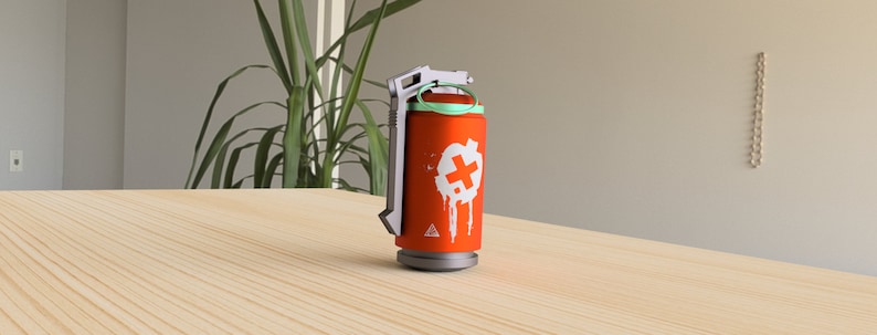 May include: A red and white grenade-shaped object with a green top and a white plus sign on the side. The object is on a wooden surface.