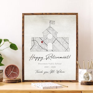 Puede incluir: Una impresión enmarcada con un diseño de mapa de un edificio, un marcador rojo y las palabras "Happy Retirement!" y "Thank you Mr. Wilson." La impresión está en un marco de madera marrón y se encuentra en un escritorio de madera.
