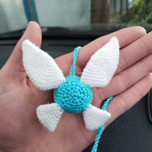 May include: A crocheted blue and white fairy charm with wings. The charm is attached to a blue cord.