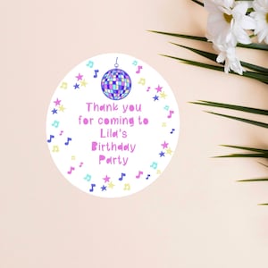 May include: A round, colorful thank you sticker with a disco ball design. The sticker says "Thank you for coming to Lila's Birthday Party".
