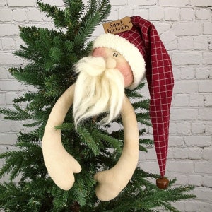 May include: A handmade felt Santa Claus tree topper with a red and white plaid hat. The topper has a white beard and a red nose. The hat has a tag that says "Saint Nicholas".