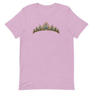 May include: A light pink t-shirt with a gold and green crown graphic.