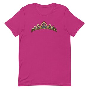 May include: A pink t-shirt with a gold and green crown design.