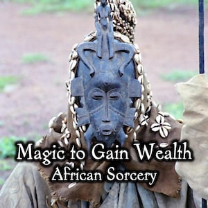 Può includere: Una persona indossa una maschera africana tradizionale con il testo "Magic to Gain Wealth African Sorcery". La maschera è blu scuro con un volto scolpito ed è adornata con conchiglie bianche e una piccola figura.