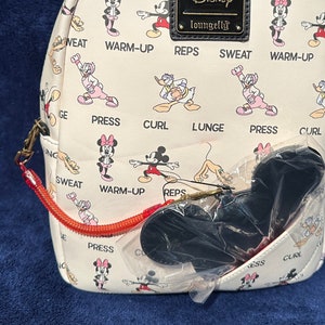 May include: A white faux leather mini backpack with a repeating pattern of Mickey Mouse and Minnie Mouse doing various exercises. The backpack has a black Loungefly tag with the word "Disney" on it. The backpack has a red zipper and a black Mickey Mouse ear charm.