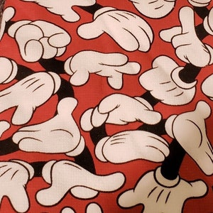 May include: Two red and white kitchen towels featuring a Mickey Mouse design. The towels have a repeating pattern of Mickey Mouse's white gloved hands on a red background. The tag on the towel reads "Disney Mickey Mouse 2pk Kitchen Towels".