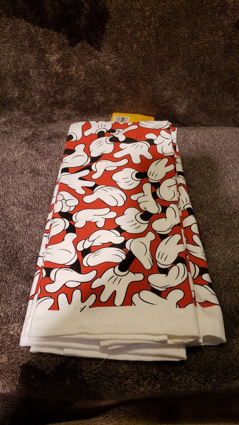 May include: A set of white kitchen towels with a red background and a pattern of black and white Mickey Mouse hands.
