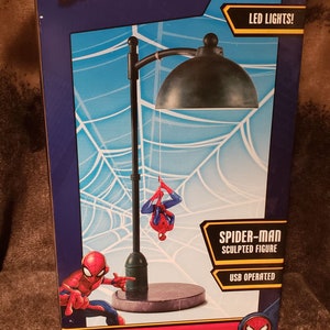 May include: A red and blue Spider-Man hanging street lamp with a sculpted Spider-Man figure. The lamp is USB operated and has LED lights. The box says "This is not a toy."
