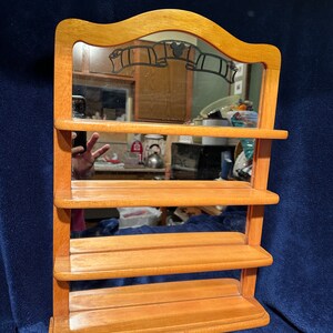 May include: Wooden shelf unit with a mirror and four shelves. The mirror has a Mickey Mouse silhouette and film reel design.