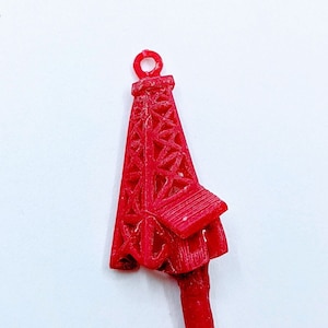 May include: A red plastic oil rig charm with a loop at the top for hanging.