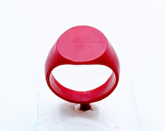 May include: A red signet ring on a white foam display stand.