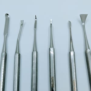 May include: Set of six stainless steel dental tools with different shaped tips. The tools are silver and have a textured handle. The tools are labelled "EUROTOOL STAINLESS STEEL PAKISTAN".