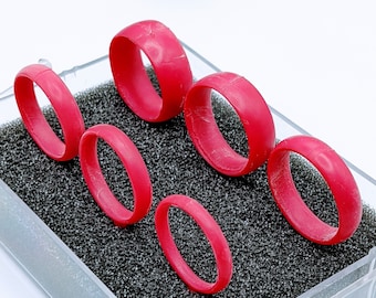 May include: A set of six red silicone rings in a clear plastic box with a black foam insert. The rings are all different sizes.
