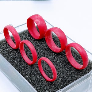 以下が含まれることがあります： 透明なプラスチック製の箱に、黒いフォーム製のインサートが入った、赤いシリコン製のリング6個セット。リングはすべてサイズが異なります。