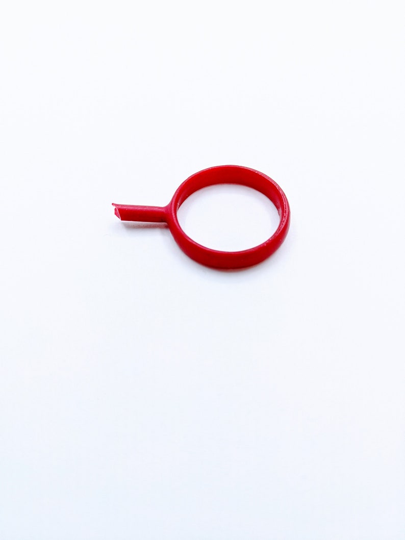 May include: A red plastic ring with a small handle attached to it.