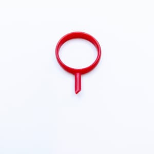 May include: A red plastic ring with a pointed tip, resembling a map marker.