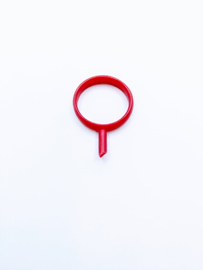 May include: A red plastic ring with a pointed tip, resembling a map marker.