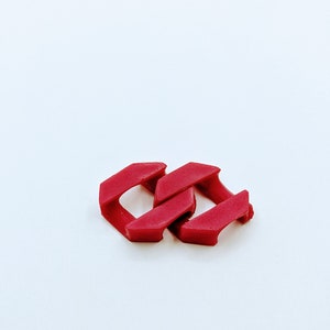 Peut inclure: Deux maillons de chaîne en plastique rouge, entrelacés, sur un fond blanc.