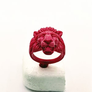 May include: A red wax ring with a lion head design. The ring is on a white foam base.