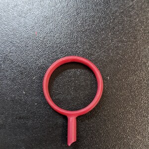 May include: A red plastic ring with a small stem extending from the bottom.