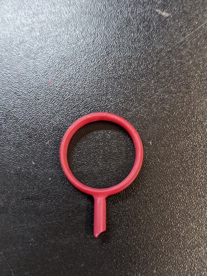 May include: A red plastic ring with a small stem extending from the bottom.