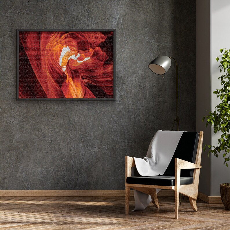 K&ouml;nnte beinhalten: Ein gerahmtes Foto einer roten und orangefarbenen Felsformation mit einem wei&szlig;en Wirbel in der Mitte. Das Foto h&auml;ngt an einer grauen Wand &uuml;ber einem schwarzen Sessel mit einer wei&szlig;en Wolldecke.