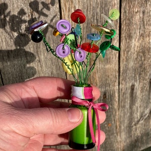 Buquês de flores com micro botões em potes de boticário de vidro.