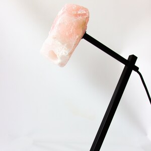 May include: A black metal desk lamp with a pink, natural crystal rock shade.