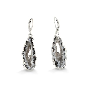 May include: A pair of silver dangle earrings featuring a unique geode design. The earrings are made of sterling silver and feature a natural agate geode with a crystal-like interior.