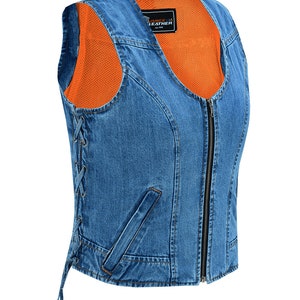 Könnte beinhalten: Eine blaue Jeansweste mit Reißverschluss und Schnürsenkeln an den Seiten. Die Weste hat ein schwarzes "Vance & Hines Leather" Etikett auf der Vorderseite.