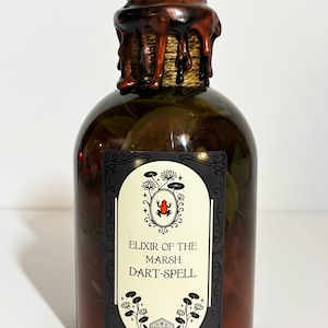 Peut inclure: Une bouteille en verre foncé avec un sceau de cire marron et une étiquette indiquant "Elixir of the Marsh: Dart-Spell". L'étiquette présente une illustration d'une grenouille rouge. La bouteille contient des feuilles et un liquide foncé.