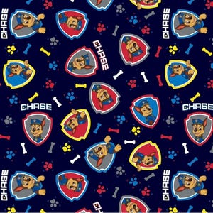 May include: Navy blue fabric featuring a repeating pattern of Chase from Paw Patrol. The design includes Chase's badge, paw prints, and bone shapes. The word "CHASE" is printed in white. The overall theme is a children's cartoon.