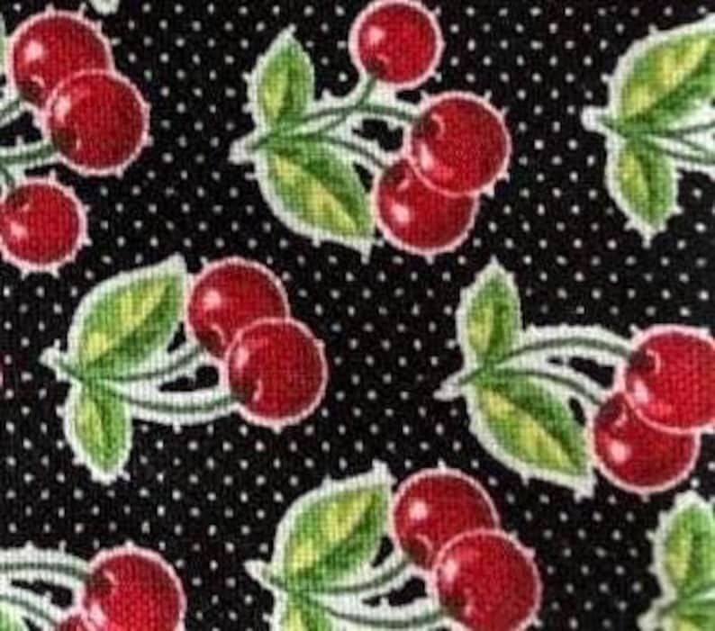 May include: Black fabric with a repeating pattern of red cherries with green leaves and white stems on a black background with white polka dots.