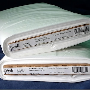 May include: Two rolls of white Bosal nonwoven fusible featherweight fabric. Each roll is labeled with the text "Style #312" and "20" width, 40 yards". The fabric is for gentle delicate support and is made of 100% polyester.