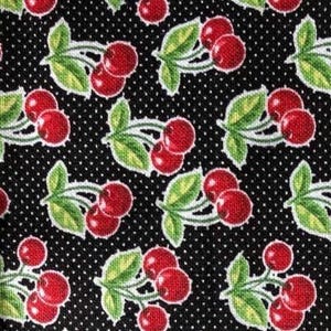 May include: Black fabric with a repeating pattern of red cherries with green stems and leaves on a white polka dot background.