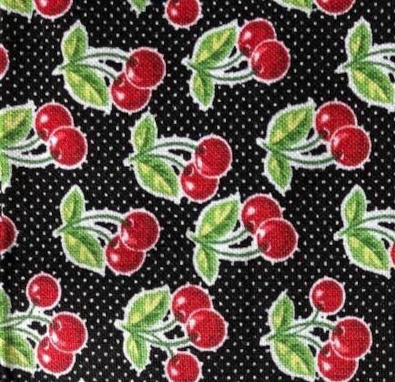 May include: Black fabric with a repeating pattern of red cherries with green stems and leaves on a white polka dot background.